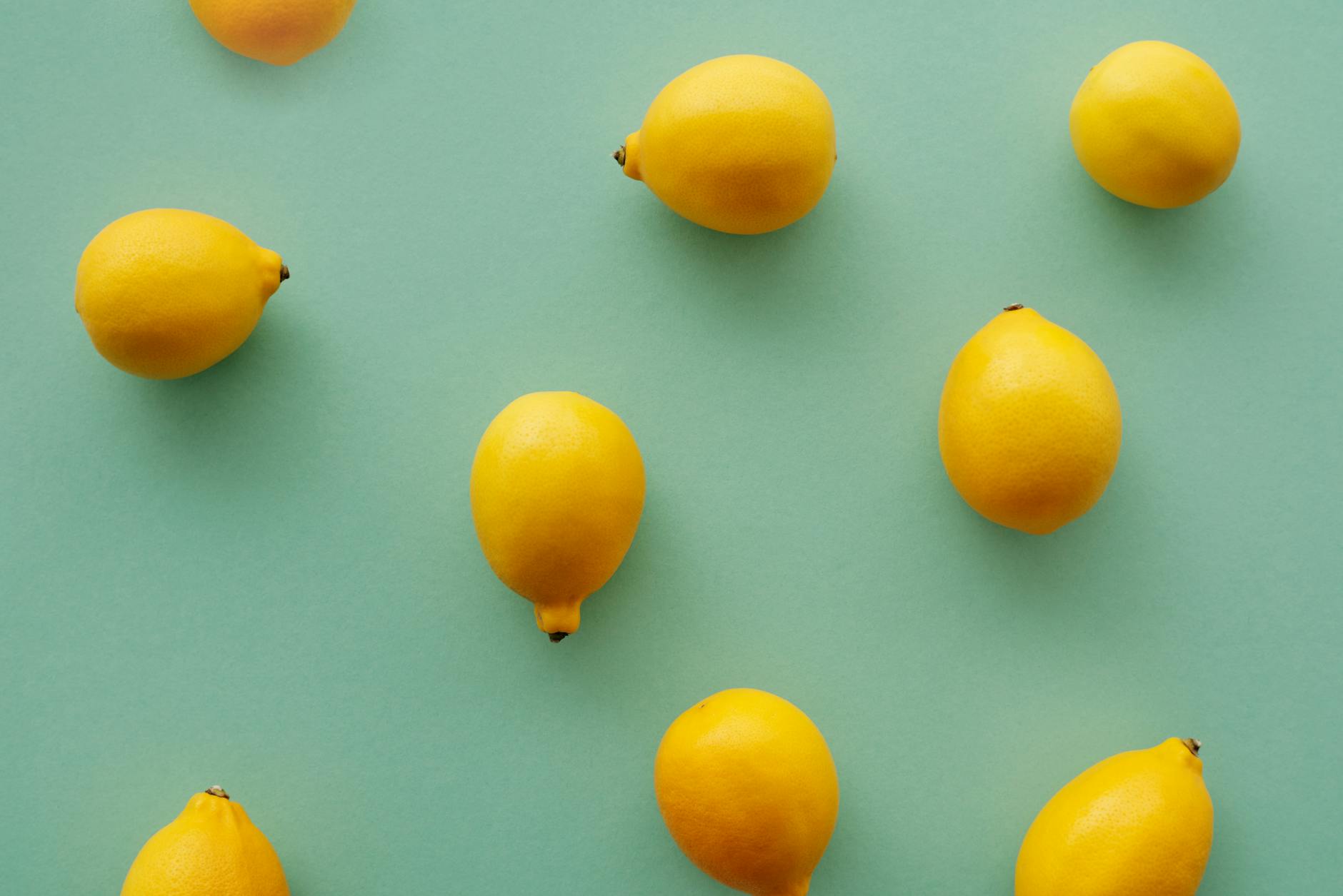 Bright yellow lemons arranged on a pastel green background, symbolizing freshness and vitality in pleasure