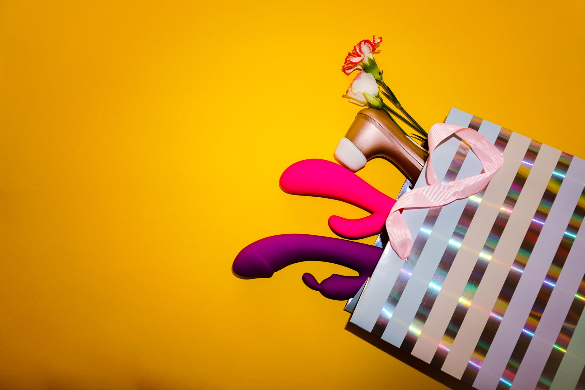 Colorful clitoral vibrators with flowers displayed against a bright yellow background